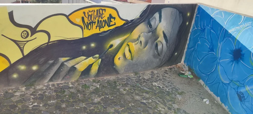 Wandbild einer jungen Frau mit dem Schriftzug „You are not alone“.