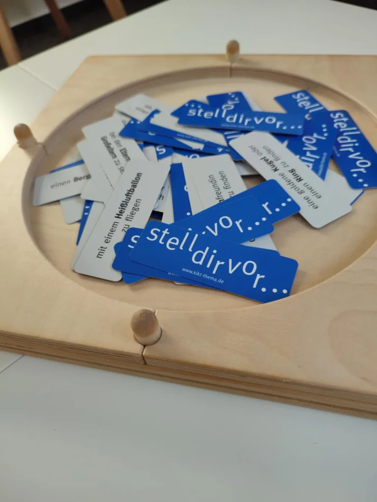Blaue Karten mit der Aufschrift „stell dir vor“ auf einem Holzbrett.