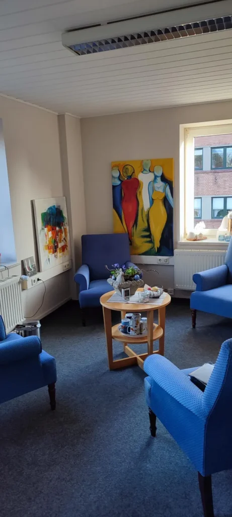 Therapieraum mit blauen Sesseln und einem runden Tisch.