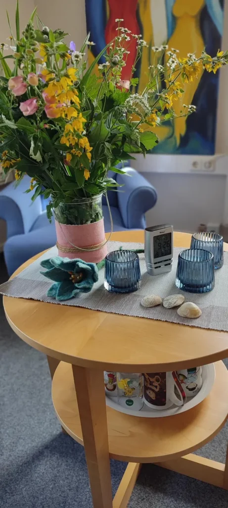 Runder Holztisch mit einem Blumenstrauß.
